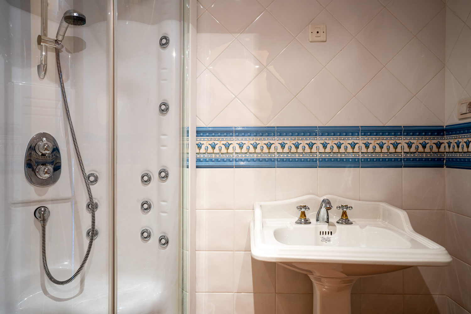 Detalle de lavabo con grifería de estilo clásico y ducha hidromasaje