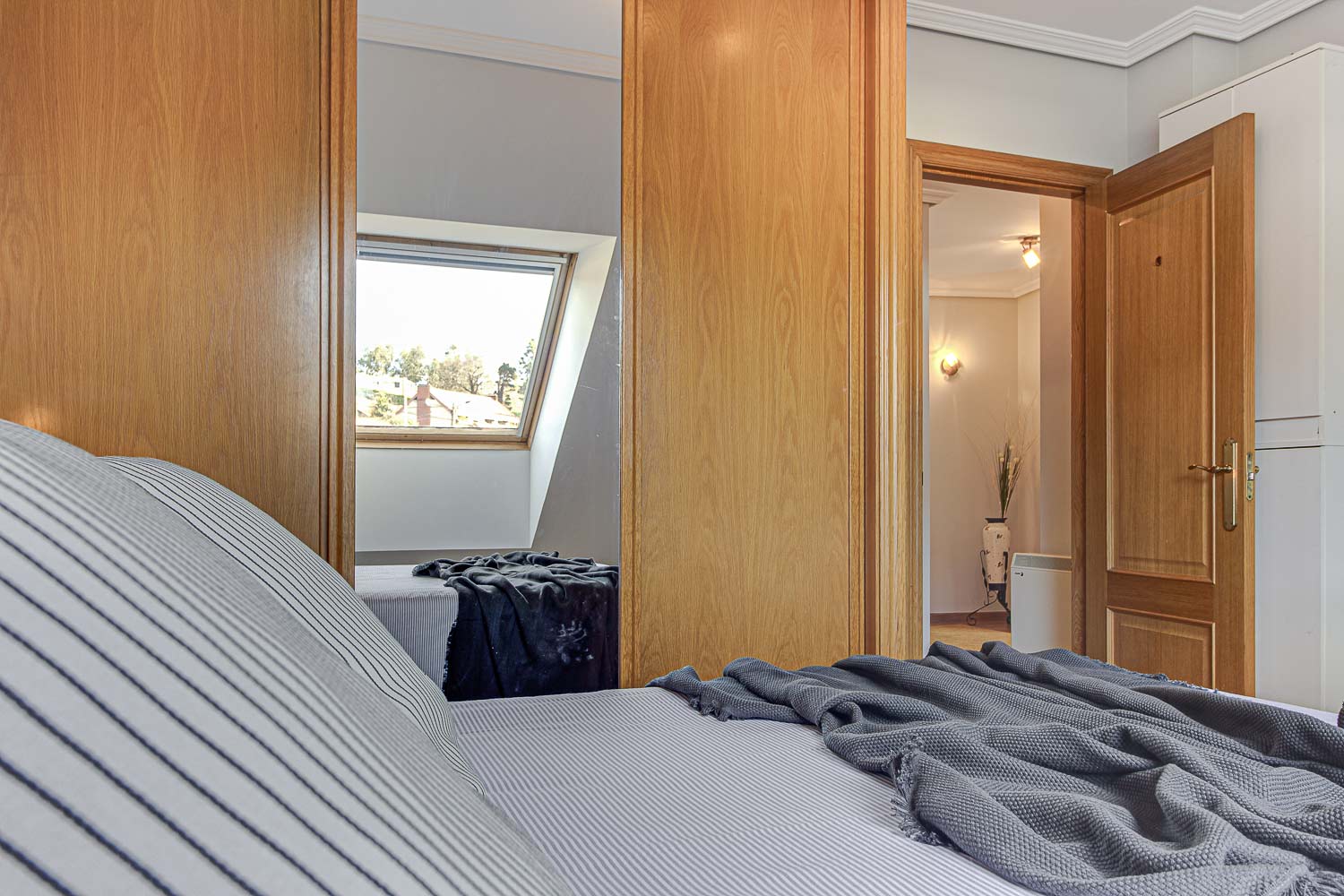 Dormitorio principal de piso en Vilaboa_ desde la cama vemos a través de la puerta abierta la entrada_ En el armario se refleja la velux_ Home Staging