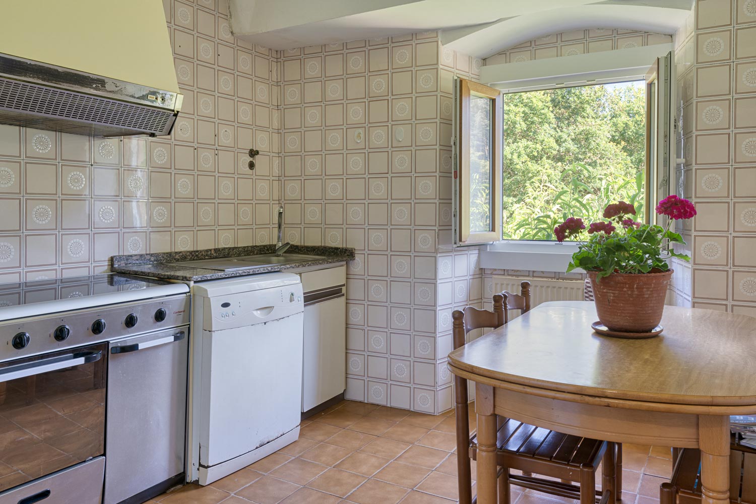 "Cocina en casa en venta en Bergondo, con azulejos decorativos, estufa y lavavajillas, mesa de comedor de madera y una ventana abierta con vistas al jardín."