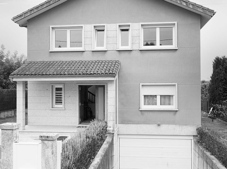 "Fachada de una casa unifamiliar moderna de dos plantas con garaje y porche en blanco y negro.