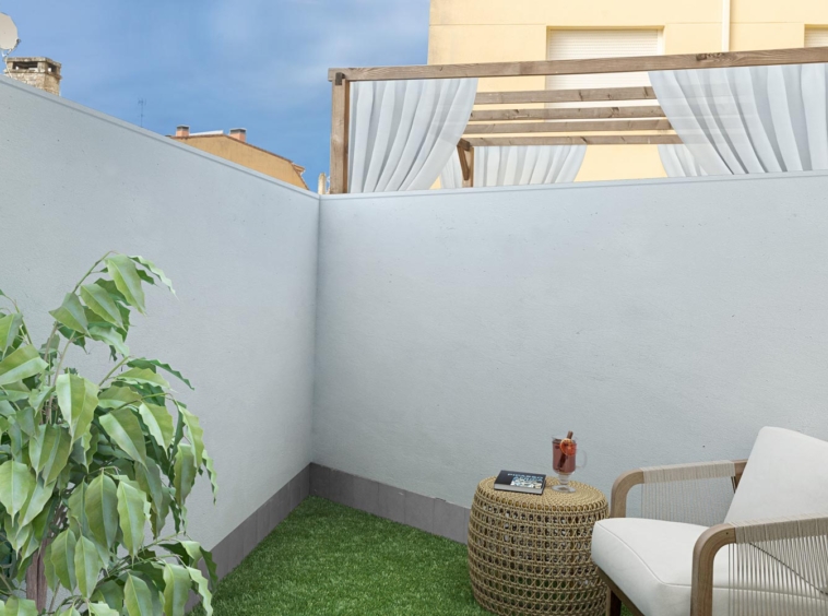 Terraza privada con decoración minimalista, césped artificial y una silla con mesa auxiliar, en venta en Sada por Morando Inmobiliaria.