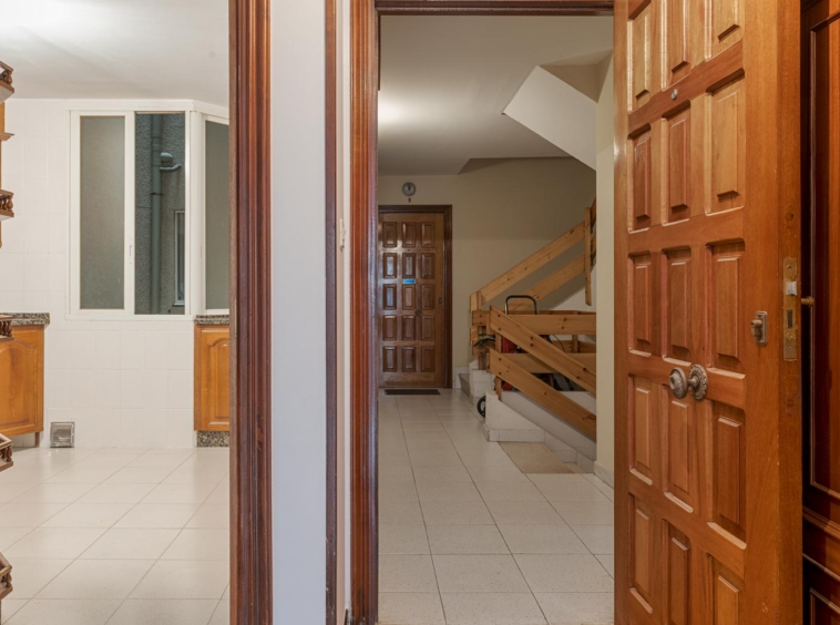 Entrada del piso con puerta de madera y acceso a la cocina, en venta en Sada por Morando Inmobiliaria.