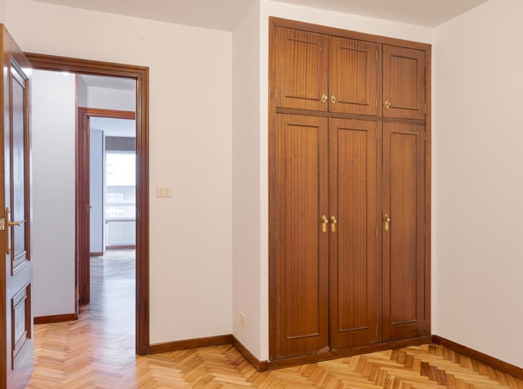 Habitación con suelo de parquet y armario empotrado de madera en vivienda en venta en Sada por Morando Inmobiliaria.