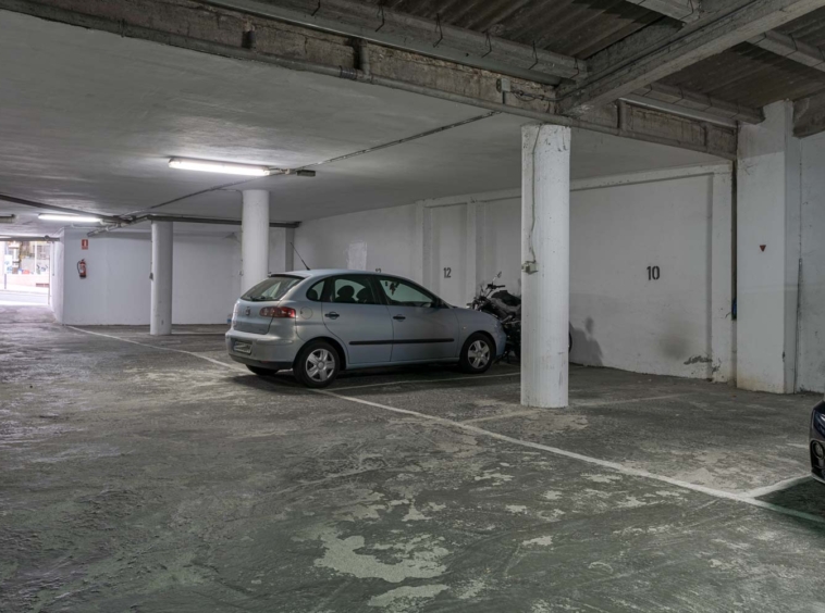 Plaza de aparcamiento cubierta con un coche plateado estacionado, disponible en venta en Sada por Morando Inmobiliaria.