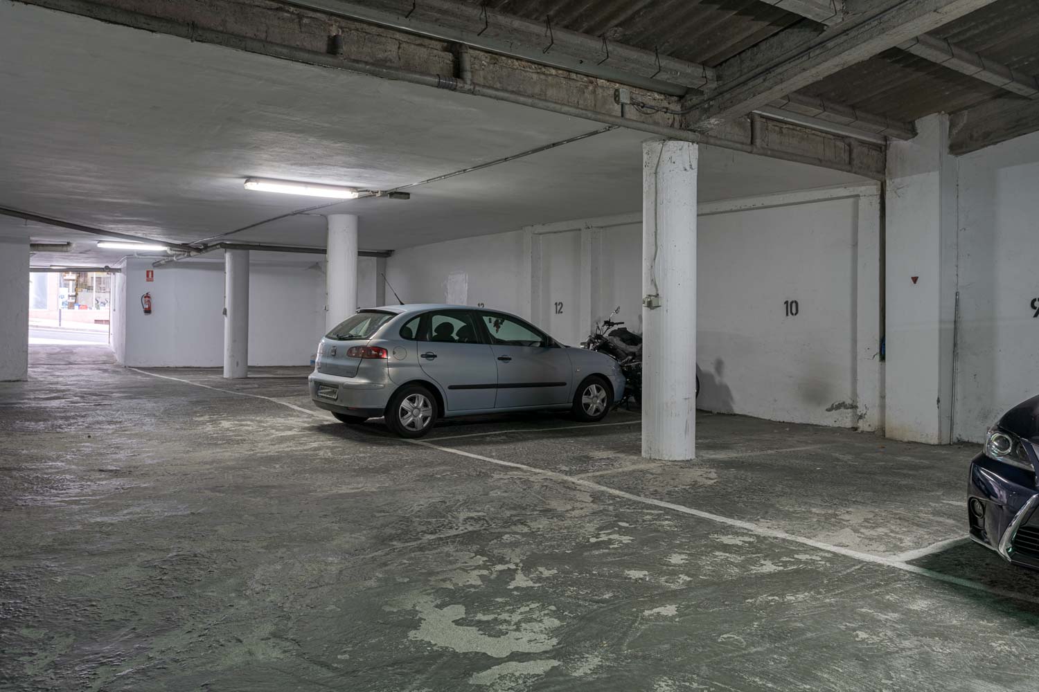 Plaza de aparcamiento cubierta con un coche plateado estacionado, disponible en venta en Sada por Morando Inmobiliaria.