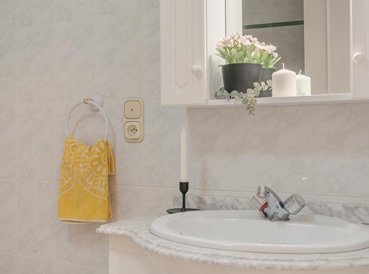 Baño luminoso con lavabo, espejo y decoración elegante en piso en venta en Sada, gestionado por Morando Inmobiliaria.