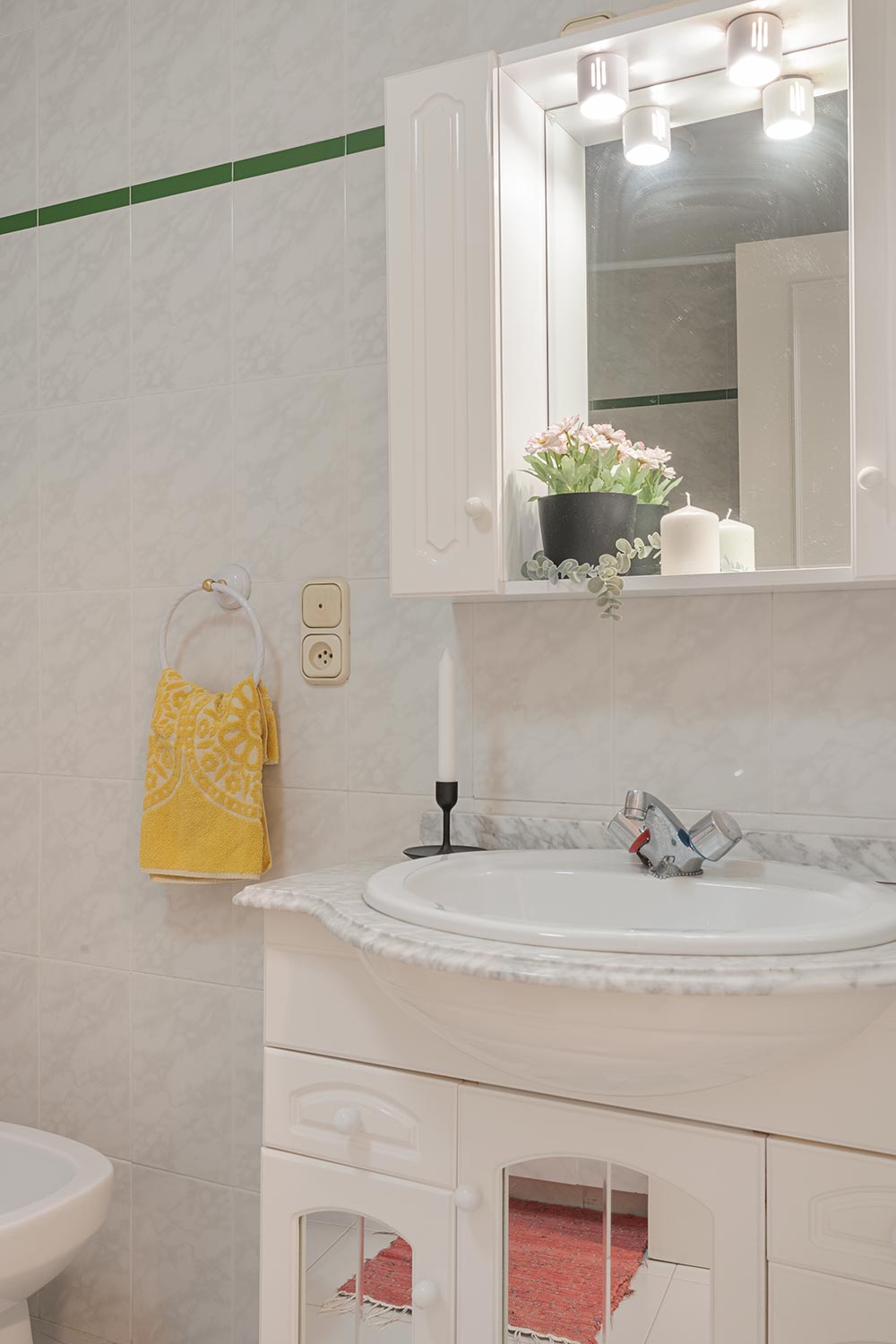 Baño luminoso con lavabo, espejo y decoración elegante en piso en venta en Sada, gestionado por Morando Inmobiliaria.