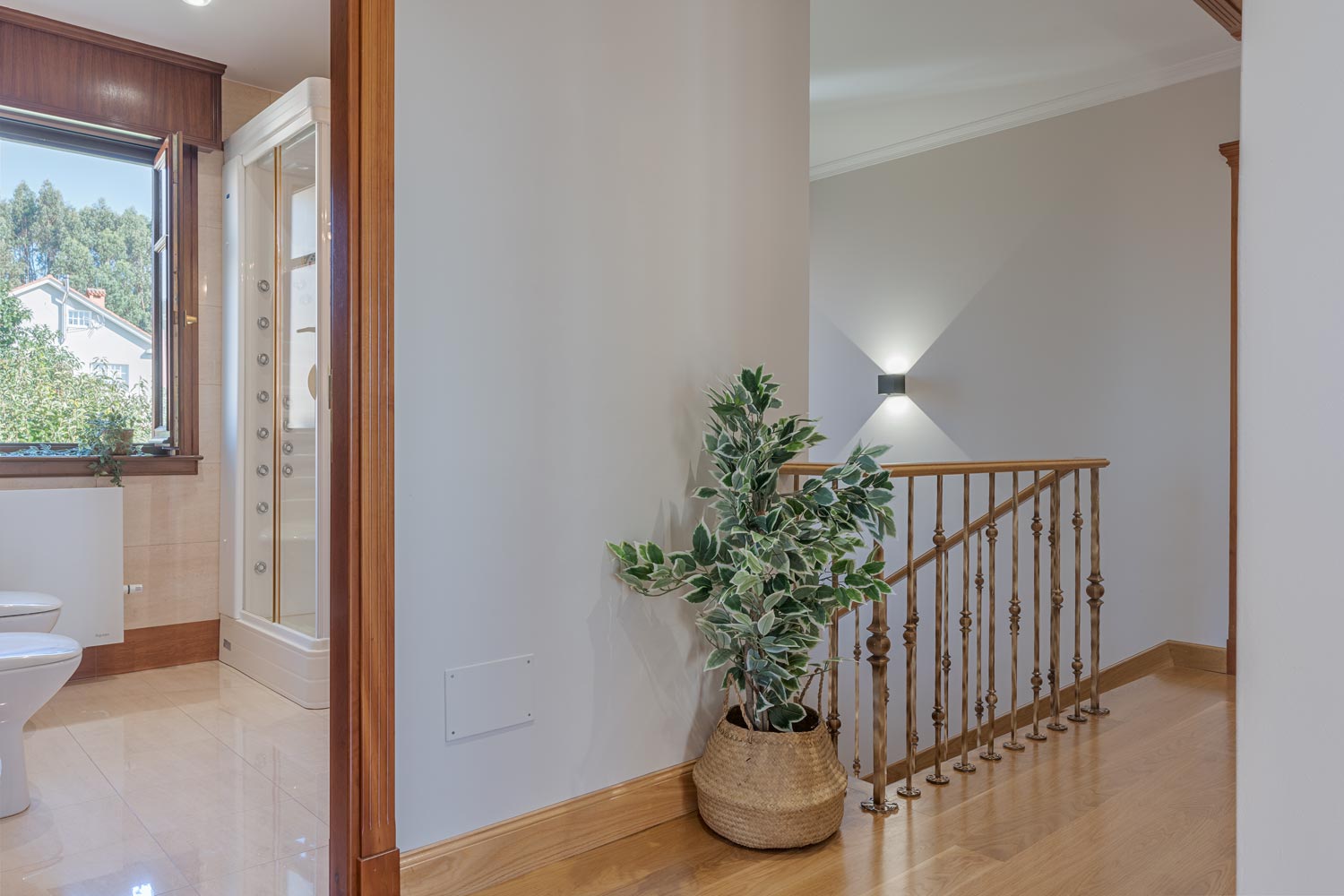 Rellano luminoso en casa clásica de Bergondo con planta decorativa, propiedad de Inmobiliaria Morando.