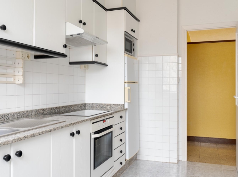 Cocina con muebles blancos y encimeras de granito en piso en venta en Sada, gestionado por Morando Inmobiliaria.