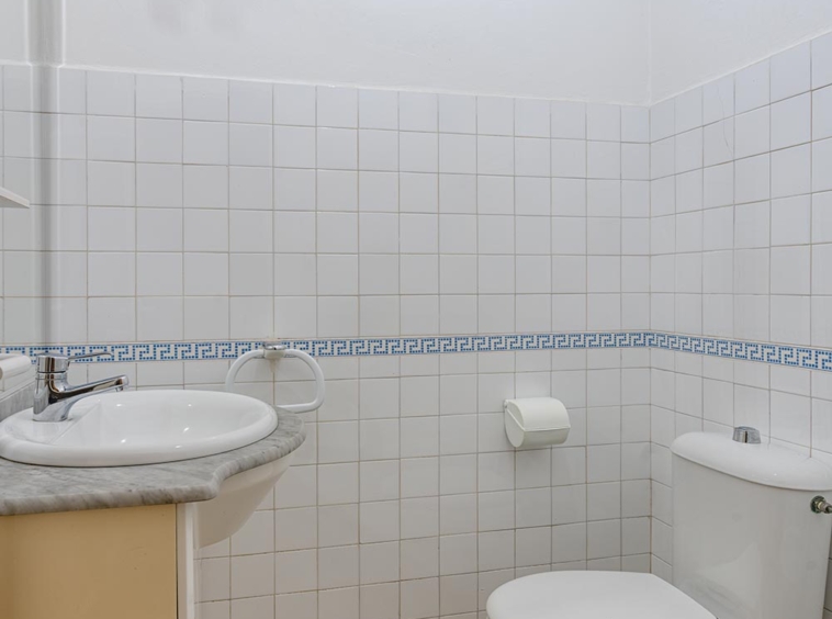 Baño con azulejos blancos y decoración en azul, lavabo y sanitario en piso en venta en Sada.