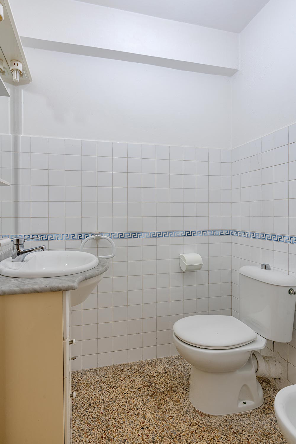 Baño con azulejos blancos y decoración en azul, lavabo y sanitario en piso en venta en Sada.