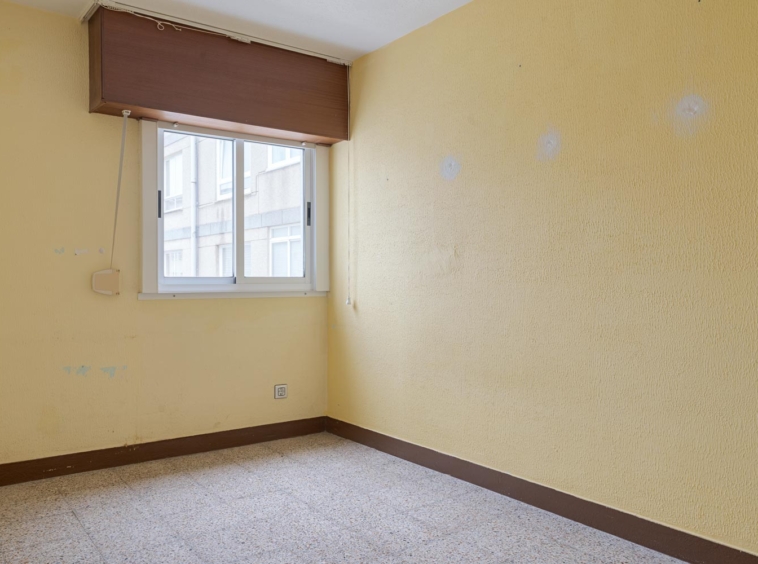 Dormitorio vacío con paredes amarillas y ventana en piso en venta en Sada.