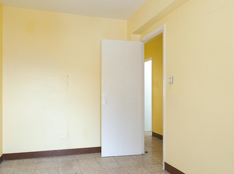 Entrada de habitación con puerta blanca y paredes amarillas en apartamento de Sada.